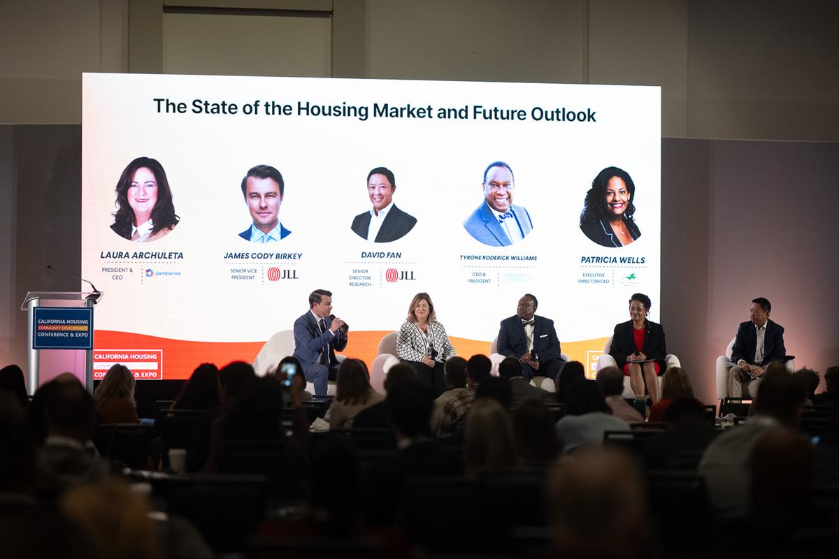A five-person panel on stage in front of a full room