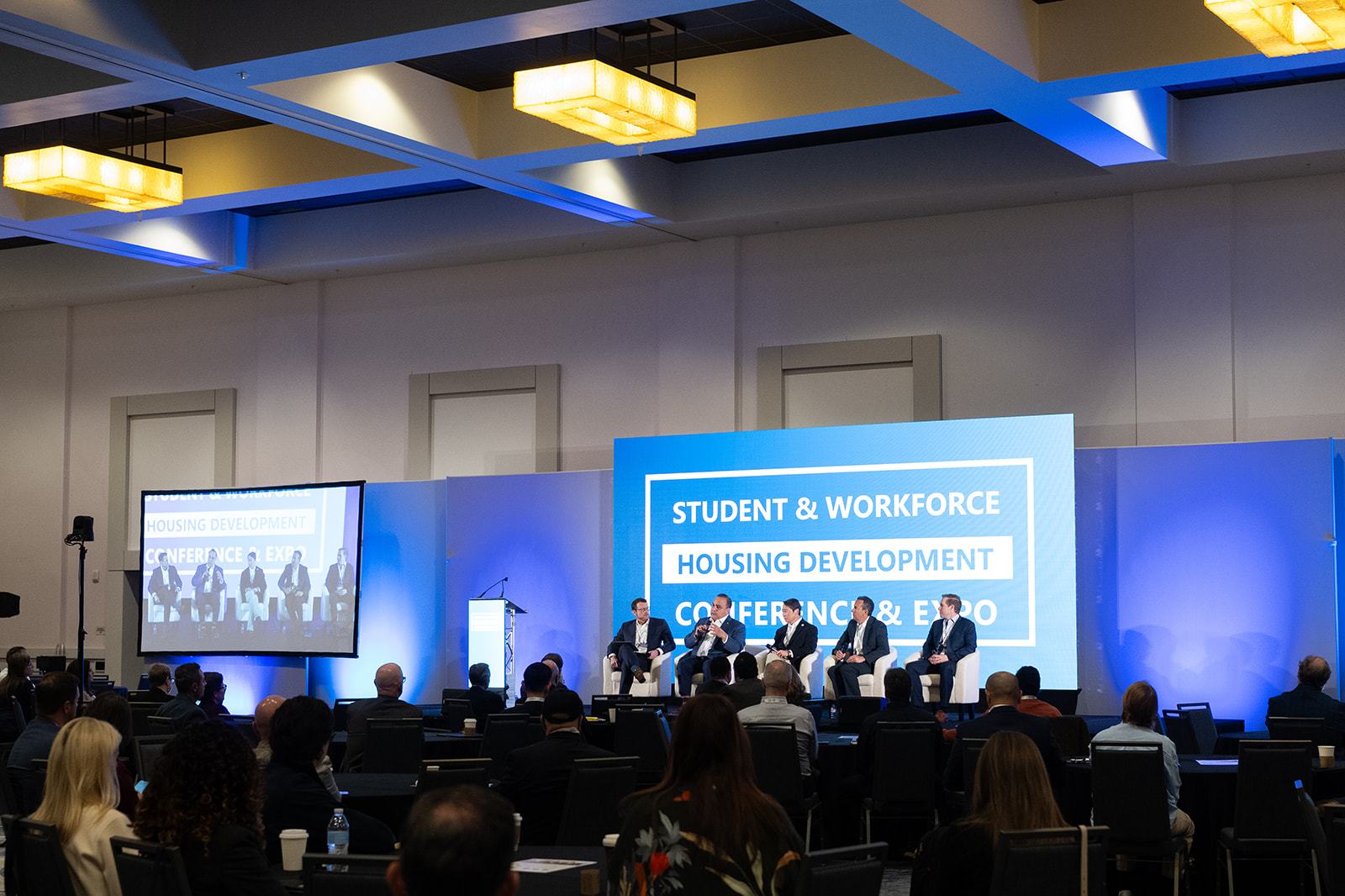 A large ballroom facing a panel on stage